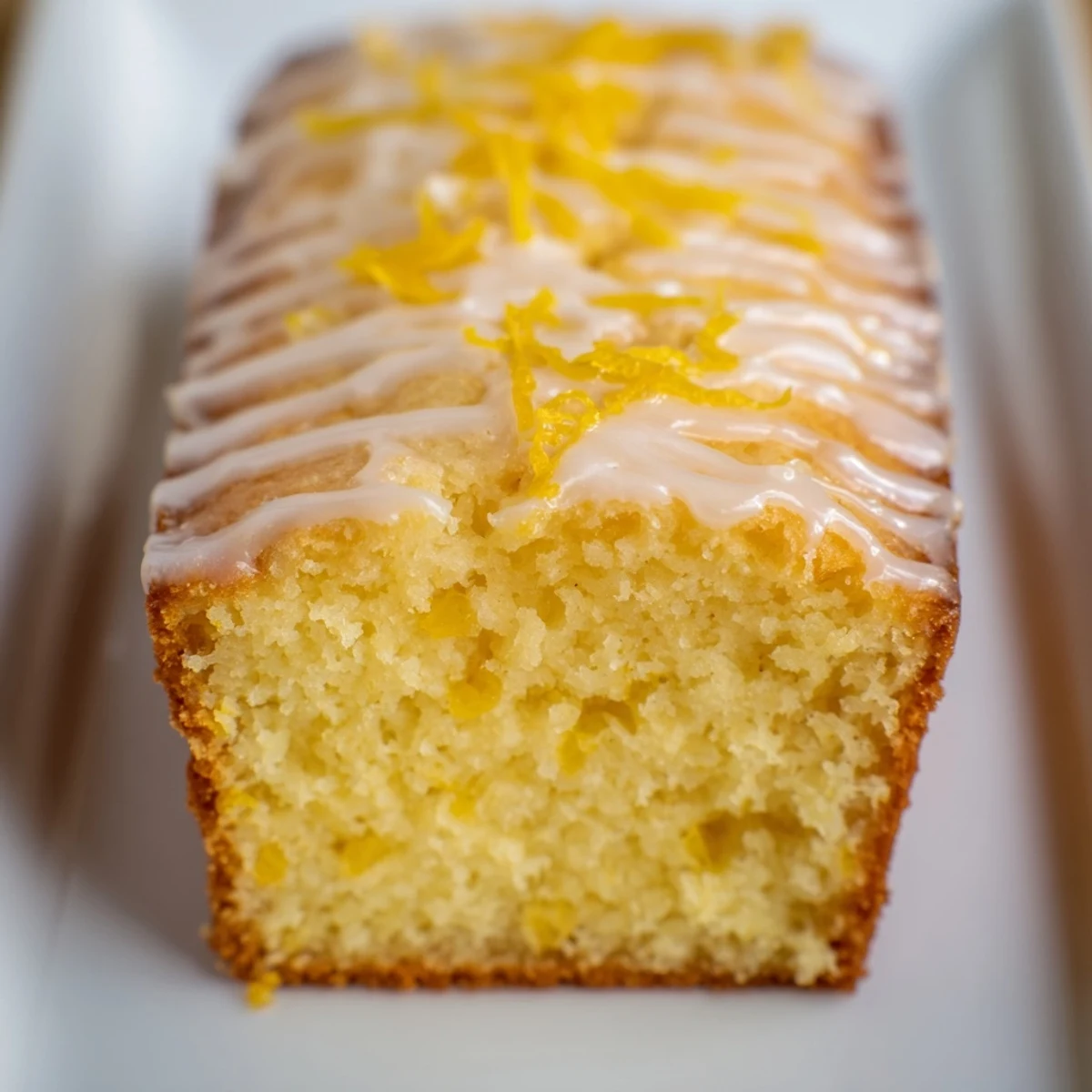 A warm, golden lemon loaf cake with a generous drizzle of tangy, white lemon icing.