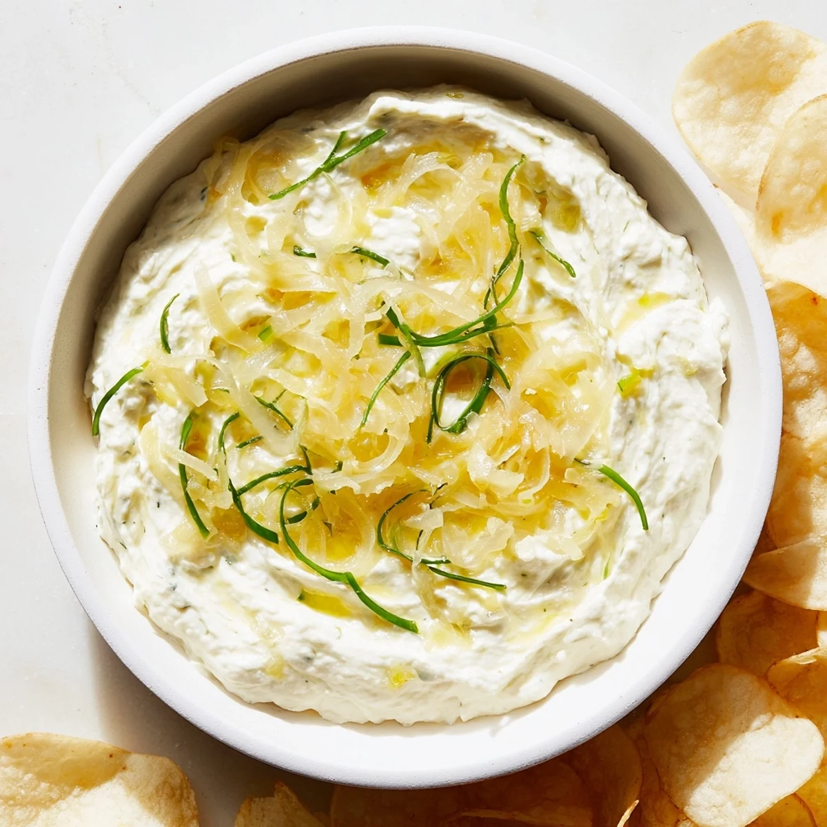 Crispy potato chips alongside a bowl of creamy onion dip, a classic American snack.