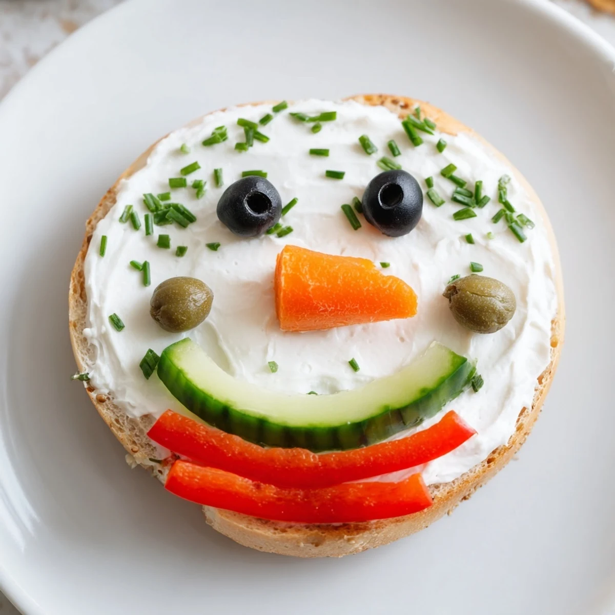 Freshly decorated Snowman Mini Bagel Sandwiches with olive eyes and bell pepper scarves, ready to eat.