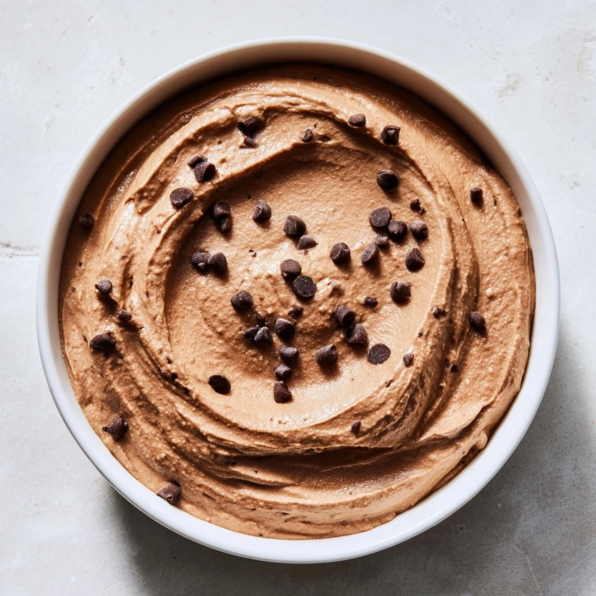Smooth, rich chocolate hummus ready to dip with fresh strawberries, a delightful vegan dessert.