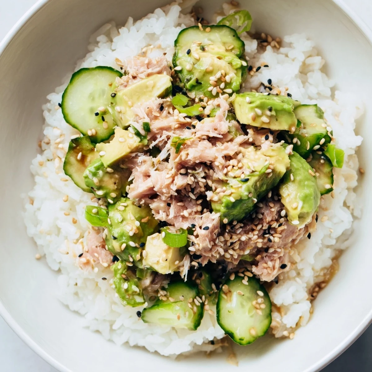 This vibrant Tuna Avocado Rice Bowl features flaky tuna, creamy diced avocado, and crisp cucumber atop warm jasmine rice, drizzled with a savory sesame-ginger dressing.