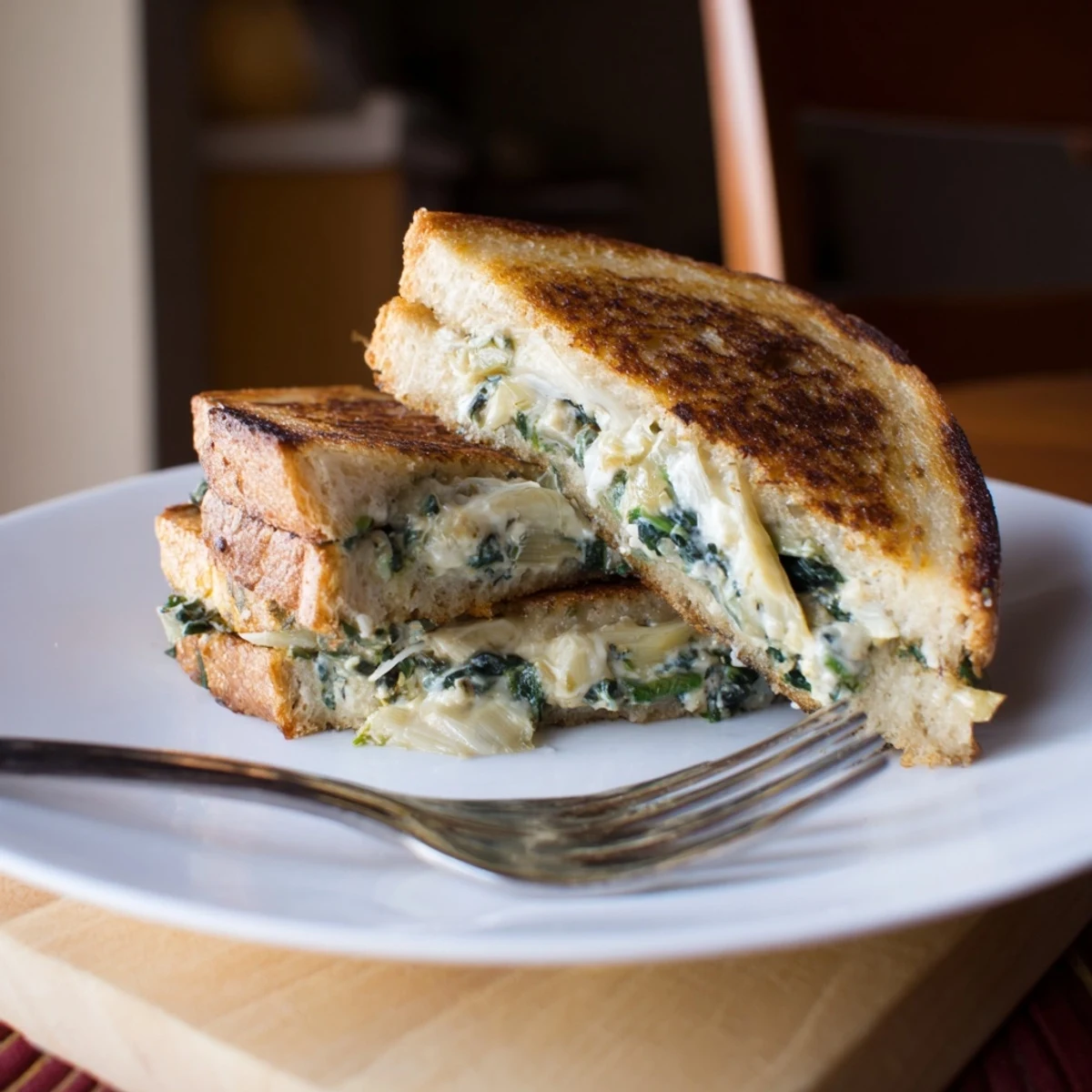 A close-up view shows the crisp, buttery bread exterior of the spinach artichoke grilled cheese.