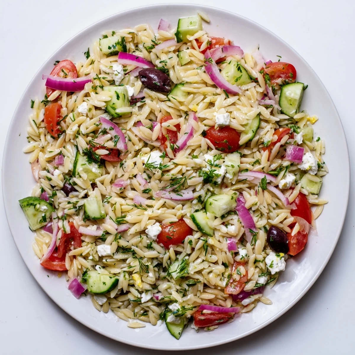 A vibrant Greek Orzo Salad with juicy tomatoes, crisp cucumber, and crumbled feta tossed in lemon-oregano dressing.