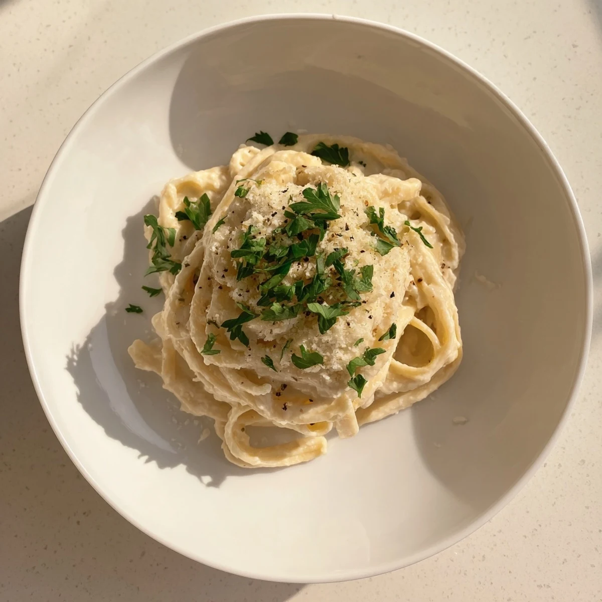 Close-up of golden roasted cauliflower florets blended into a smooth, nutmeg-scented Alfredo sauce over al dente pasta.