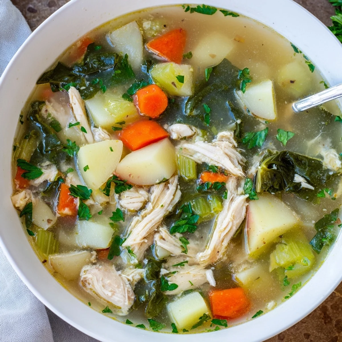 A ladle of hearty Collard Greens, Chicken and Vegetable Soup with tender potatoes, carrots, and vibrant greens.