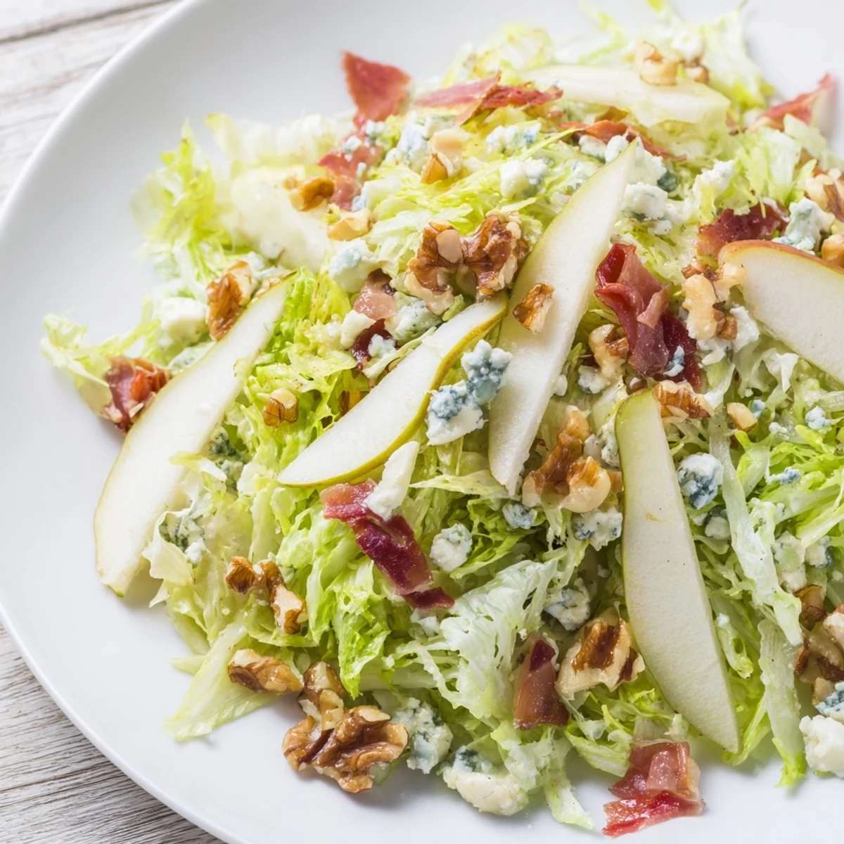 Crispy prosciutto shatters over a bed of frisée salad with sliced pears and creamy blue cheese, dressed in tangy vinaigrette for an elegant light lunch.
