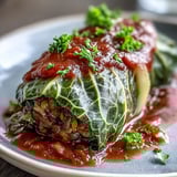 A close-up view of a savory Baked Vegan Cabbage Roll, revealing a hearty filling of lentils and brown rice on a rustic plate.