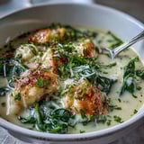 A pot of simmering Garlic Parmesan Chicken Soup with tender chicken pieces and fresh spinach, steam rising from the velvety broth.