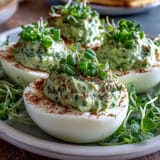 Fresh green avocado deviled eggs, garnished with chives and dill, perfect for spring parties and healthy snacking.