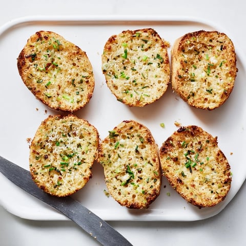 Freshly baked golden cloud bread savory toast topped with chopped chives and parsley, perfect for dipping in creamy tomato soup.