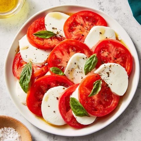 Fresh sliced tomatoes and mozzarella rounds, artfully arranged and ready to serve with basil.
