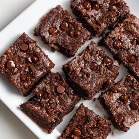 A plate of moist Greek yogurt brownies, topped with chocolate chips for extra richness.