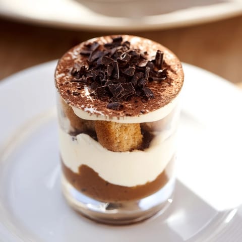 These elegant deconstructed tiramisu shots showcase moist biscuit layers, covered by light, airy mascarpone cream, perfect for dessert.