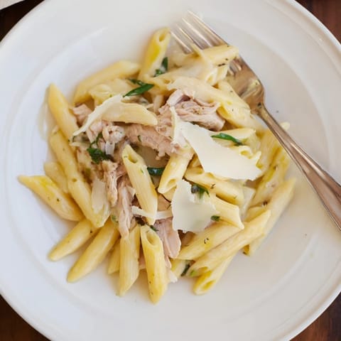 A close-up of Roasted Garlic Chicken Penne shows steaming pasta, juicy chicken pieces, and a rich, velvety roasted garlic cream sauce ready to serve.