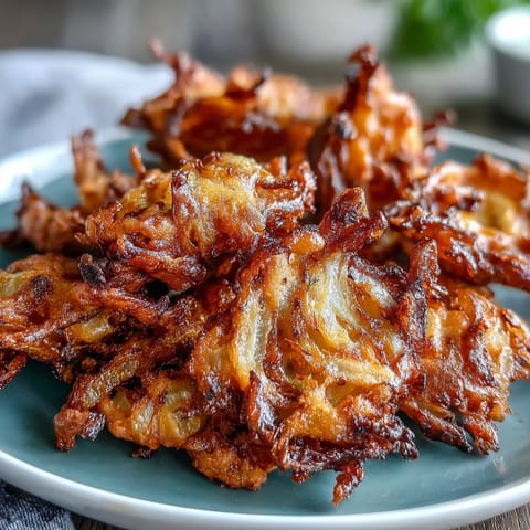 Fragrant air fryer onion bhajis with thinly sliced onions, gram flour, and turmeric, served hot and crunchy.  