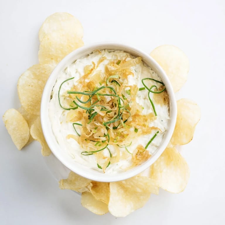 Cool, creamy onion dip ready to scoop up with salty potato chips at your gathering.