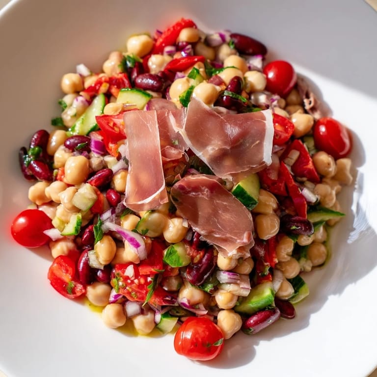 A refreshing bowl of Dense Bean Salad with Prosciutto, drizzled with zesty vinaigrette, ready to serve.