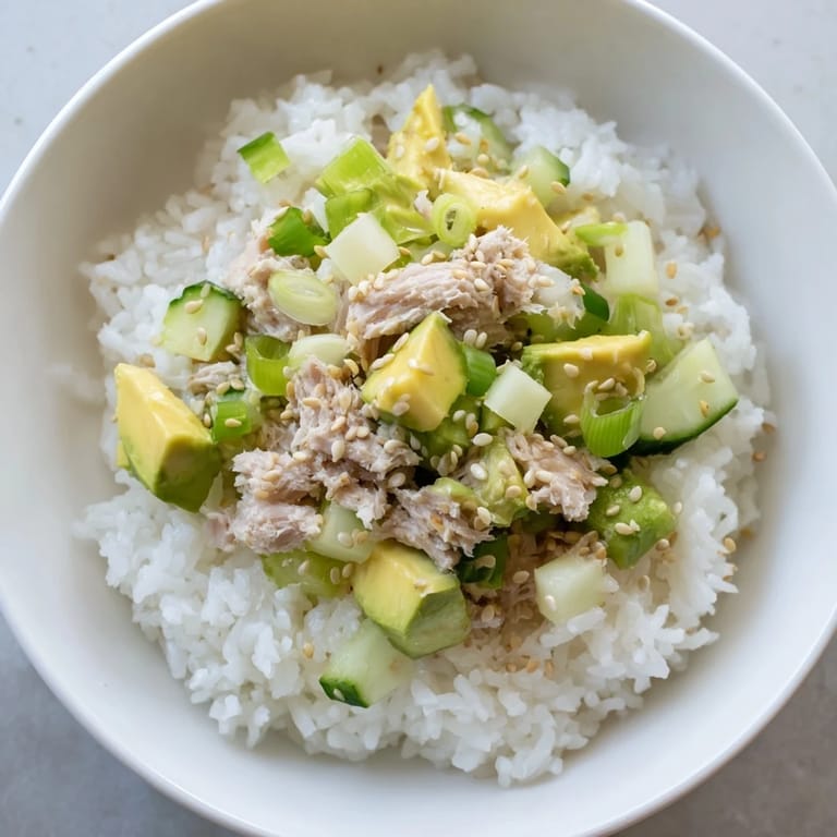 Perfect for a quick weeknight meal, this Tuna Avocado Rice Bowl offers a satisfying mix of textures and fresh flavors, garnished with toasted sesame seeds and nori.